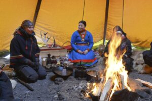 Människor runt lägerelden i ett tipi-tält